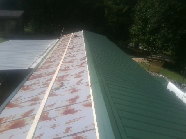 Old rusted panels beside newly installed green metal roofing — Wind Damage Roof Repair by Roofing Brothers in Demotte