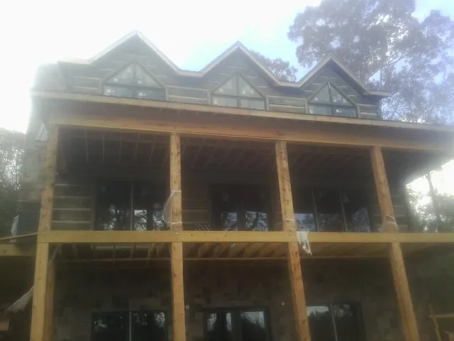 Dormers and porch framing on a large log home under construction — Roof Coating work by our crew in Demotte