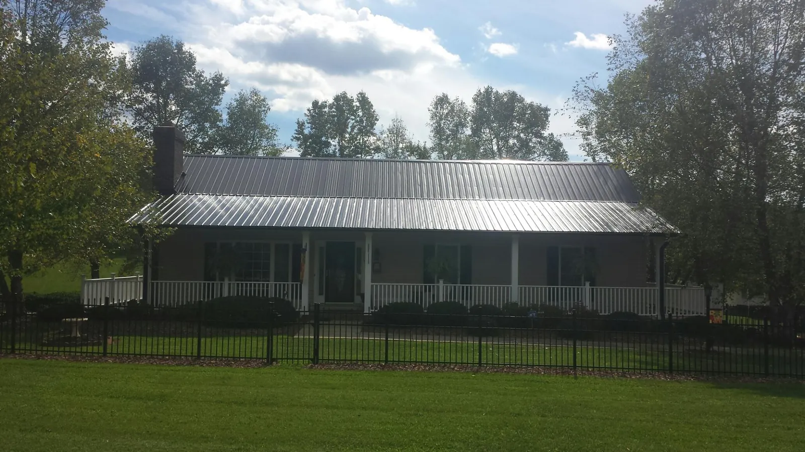 Gray metal roof on a brick ranch with a full width front porch — Gutter Guard Installation work by our crew in Demotte