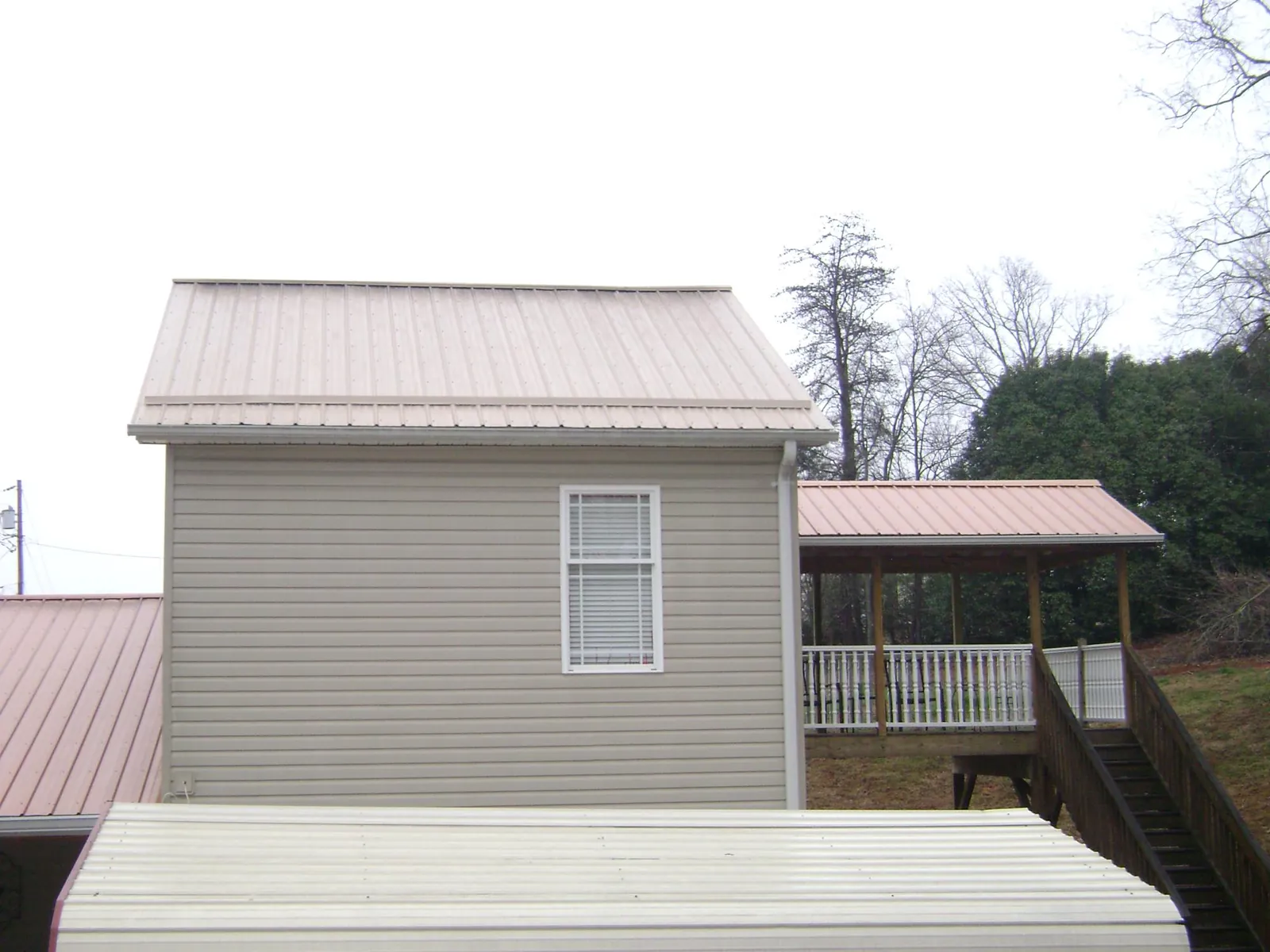 Tan metal roofs on a two story addition and attached porch, from a Roof Replacement job in Demotte